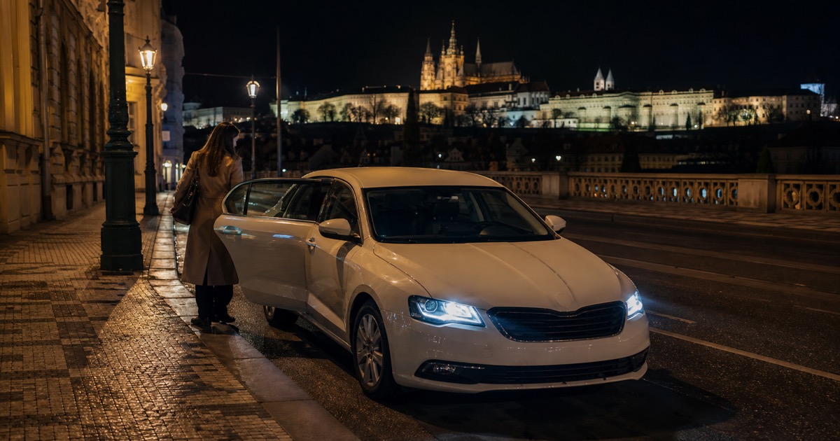 Cestující nastupuje do taxi v noční Praze pod Pražským hradem